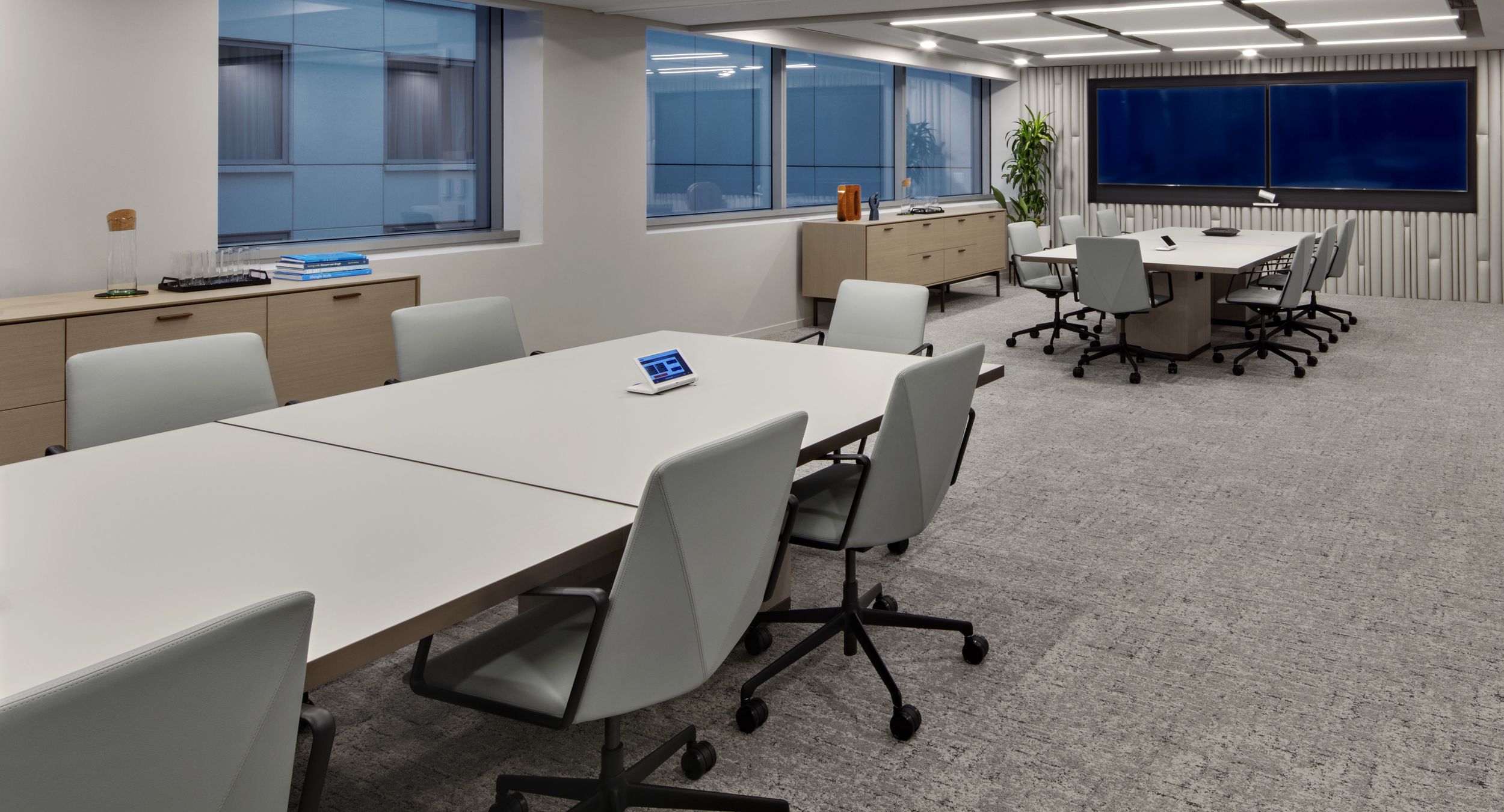 Reconfigurable MOTUS tables with back-painted Windham grey glass surfaces and deep bronze trim are perfectly complemented by a pair HALO credenzas.